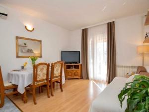 a living room with a table and chairs and a television at Stella with pool & heated jacuzzi in Zmijavci