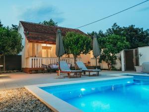 a pool with chairs and umbrellas next to a house at Stella with pool & heated jacuzzi in Zmijavci