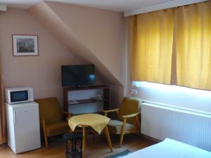 a living room with a tv and a table and chairs at Hejő Apartman in Miskolctapolca
