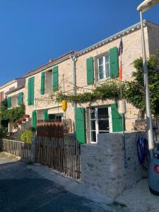 a brick building with green shutters and a fence at La maison du pêcheur in Dolus d'Oléron