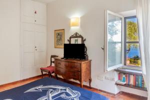 - un salon avec une télévision sur une commode et une fenêtre dans l'établissement Villa Luce, à Porto Santo Stefano