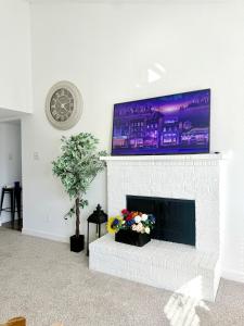 a living room with a white brick fireplace with a flat screen tv at Luxe, Family Friendly, Spacious & Private Entrance in Addison