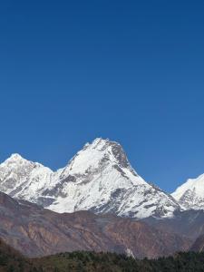 a snow covered mountain with a blue sky in the background at Hotel white palace in Syābru Bensi