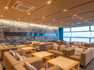 a waiting room with couches and tables and a stone wall at LiVEMAX Sakishima Cosmo Tower Hotel in Osaka +13 photos
