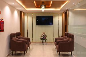 a row of chairs in a waiting room with a tv at Good One Suites in Bengaluru