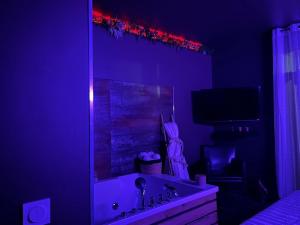 a bathroom with a sink and a mirror with purple lights at Appartement Romantique Exceptionnel in Lorette
