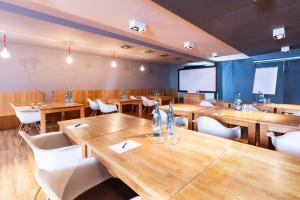 a restaurant with wooden tables and white chairs at Alpenhotel Ammerwald in Reutte +31 photos