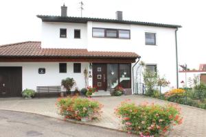 une maison blanche avec des fleurs devant elle dans l'établissement Ferienwohnung Haus Michel, 90 Qm, à Uhldingen-Mühlhofen
