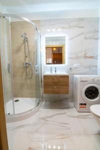 une salle de bain avec douche et lavabo et une machine à laver dans l'établissement Maya's Flats & Resorts 48 - Szafarnia, à Gdańsk