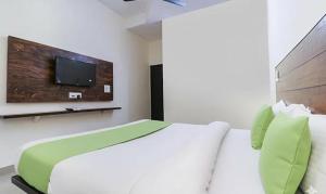 a bedroom with a bed with a tv on the wall at FabHotel Red Ark Inn in Lāndrān