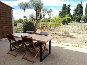 a wooden table with four chairs sitting around it at Appartement avec jardinet dans mas équestre in Saint-Laurent-dʼAigouze