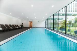 a swimming pool in a building with glass windows at Alpenhotel Ammerwald in Reutte