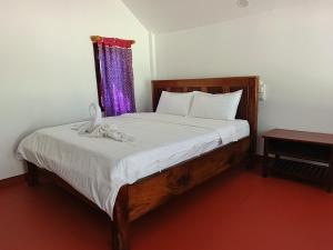 a bedroom with a wooden bed with a purple curtain at Namnoncave Resort in Ban Namnon