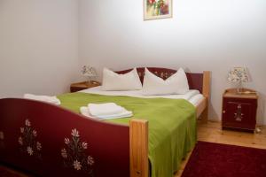 a bedroom with a bed with a green comforter at Amadé Pension in Siculeni