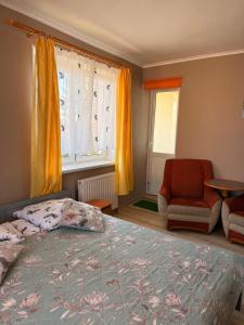 a bedroom with a bed and a chair and a window at Dom wczasowy Max in Darłowo