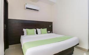 a bedroom with a large white bed with green pillows at FabHotel Red Ark Inn in Lāndrān