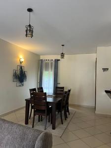 カンパラにあるHanik Homestay 3BDRMのダイニングルーム(テーブル、椅子、冷蔵庫付)