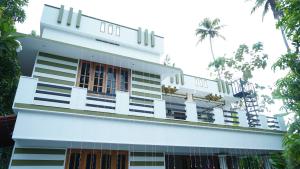 Un edificio blanco con palmeras delante. en Avaiaa, en Varkala