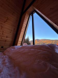 a bed in a room with a large window at Macko’s cabin in Băile Tuşnad