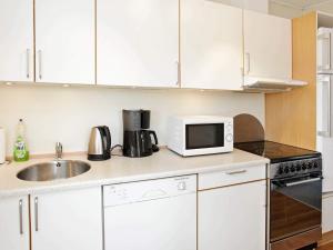 バイアス・スタンにある4 person holiday home in Vejers Strand-By Traumの白いキャビネットとシンクと電子レンジを備えたキッチン +27枚の写真