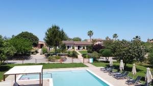 a swimming pool with lawn chairs and umbrellas at Agroturismo Can Pere Rei in Son Serra de Marina