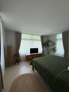 a bedroom with a bed and a flat screen tv at Villa Verde Ko Phangan in Haad Pleayleam