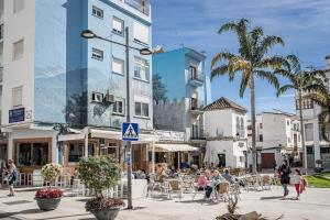 a city street with people sitting at tables and buildings at Seaclub Suites Estepona in Estepona