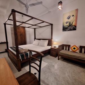 a bedroom with a canopy bed and a chair at Sinali Villa in Habaraduwa