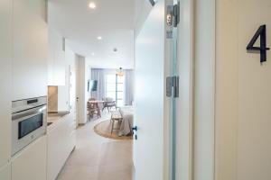 a kitchen with white cabinets and a living room at Seaclub Suites Estepona in Estepona +155 photos