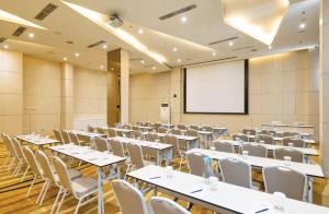 a conference room with tables and chairs and a screen at Artotel Harmoni Jakarta in Jakarta +33 photos