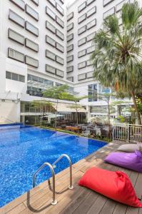 a large swimming pool with purple and purple pillows next to a building at Artotel Harmoni Jakarta in Jakarta