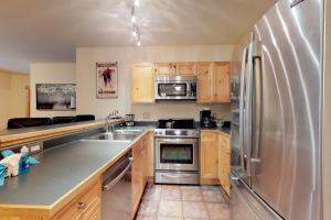 eine Küche mit Küchengeräten aus Edelstahl und Holzschränken in der Unterkunft Tenderfoot Lodge 2605 in Snake River Health Services Incorporated Heliport