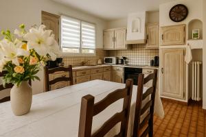 une cuisine avec une table et un vase de fleurs dans l'établissement maison individuel proche des châteaux et Amboise avec jardin clos, à Pocé-sur-Cisse