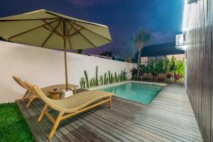 een patio met een stoel, een parasol en een zwembad bij Oasis Pandawa 1A - Just Built! Perfect Getaway Villa with Pool in Ungasan