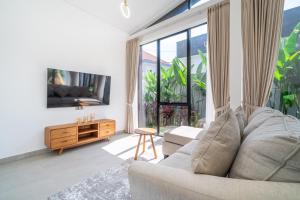 een woonkamer met een bank en een groot raam bij Oasis Pandawa 1A - Just Built! Perfect Getaway Villa with Pool in Ungasan