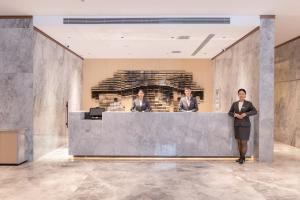 three people standing behind a counter in a lobby at Jinyi Select Hotel Hohhot Juhaicheng International Convention and Exhibition Center in Hohhot