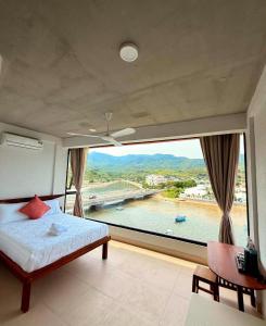 a bedroom with a large window with a view of a river at New Yêu Biển homestay in Vĩnh Hy