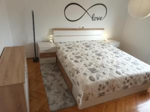 a bedroom with a bed with alove sign on the wall at Apartment Carmen in Brezje