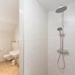 a white bathroom with a shower and a toilet at Bed & Breakfast Orvelte in Orvelte