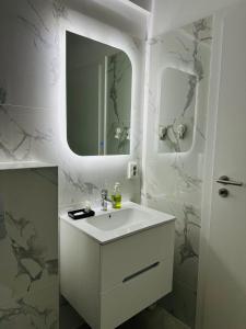 a white bathroom with a sink and a mirror at Caro Studio in Tunari
