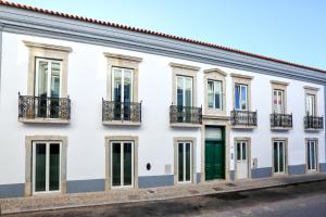 a white building with green doors and windows at Green Essence Duplex in Faro by Misha's Place in Faro