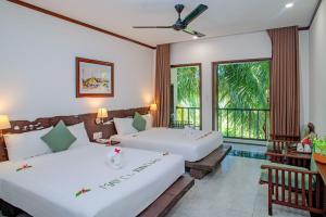 two beds in a hotel room with two large windows at Mayci Eco Boutique Hotel Hoi An in Hoi An +49 photos