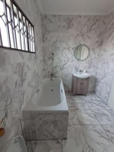 Un baño con bañera blanca y lavabo. en La Serenita, en Mbabane