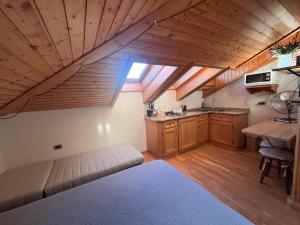 a room with a bed and a kitchen with wooden ceilings at Mansardina Il Nido in Padola