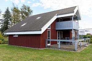 a red barn with a deck and a balcony at Seeschwalbe Classic 77 in Rechlin