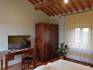 a bedroom with a desk and a tv and a wooden cabinet at Tenuta Seripa in Sassetta