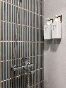 een badkamer met douche en twee zeepdispensers aan de muur bij Yoshi Hotel - Tainan Sinmei Branch in Tainan