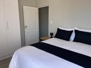 een slaapkamer met een groot wit bed met blauwe kussens bij Coastal Charm St Francis Bay in Vosburg +1 foto