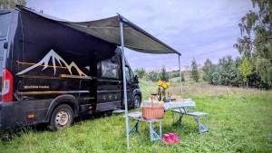a black truck parked in a field with a tent at Ubytování v obytném voze 