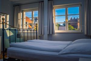 a bedroom with a bed and two windows at Hotel Obertor in Ravensburg